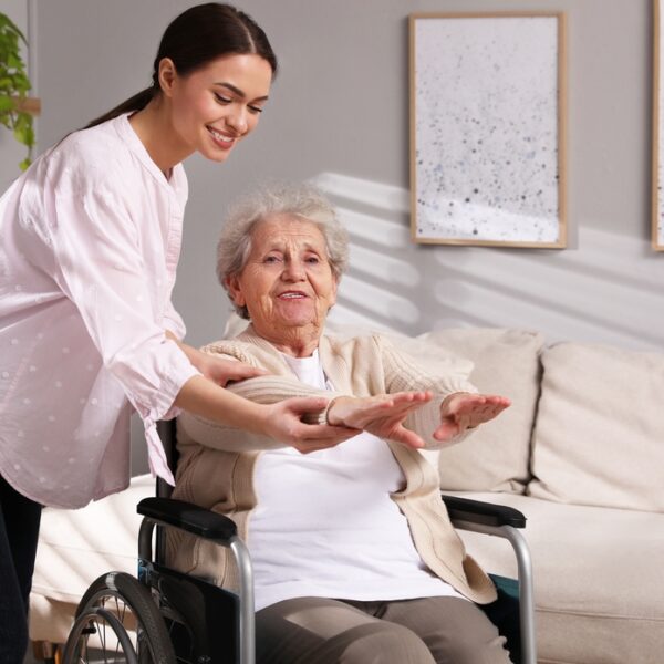 Senior,Woman,In,Wheelchair,Doing,Physical,Exercise,And,Young,Caregiver